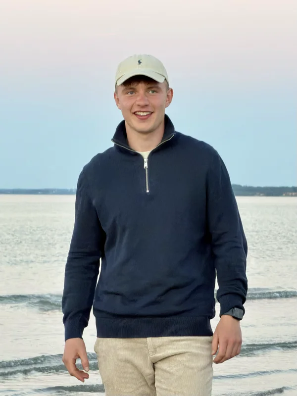 Aaron Weege am Strand, helle Cap, dunkelblauer Pullover