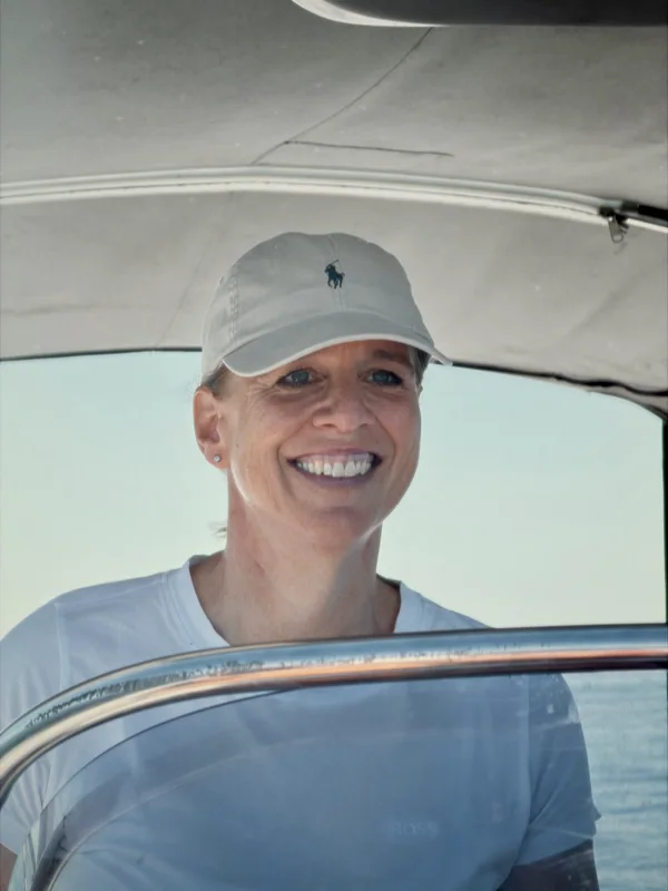 Katrin Weege mit Cap auf dem Boot, lächelnd in die Kamera